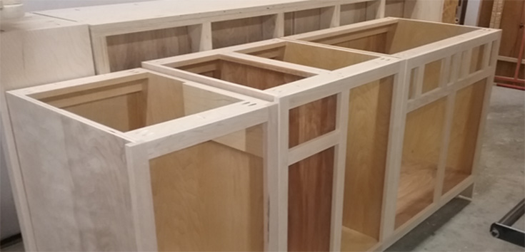Unfinished wooden cabinet frames in a workshop setting.